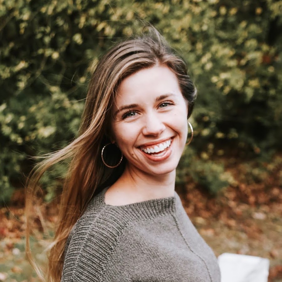 Knitty Natty smiling outdoors in a hand-knit sweater