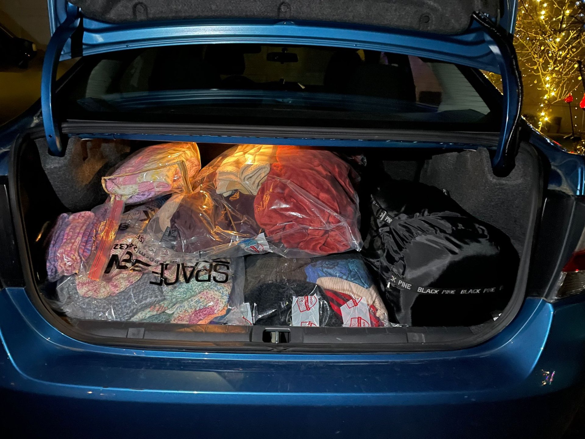A car trunk packed full of vacuum-sealed bags of donated knitwear ready to ship