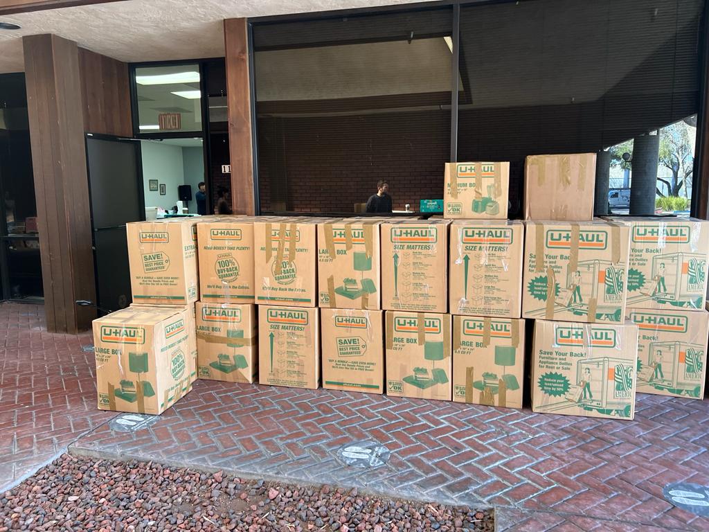 A stack of packed shipping boxes of donated knitwear waiting outside a building