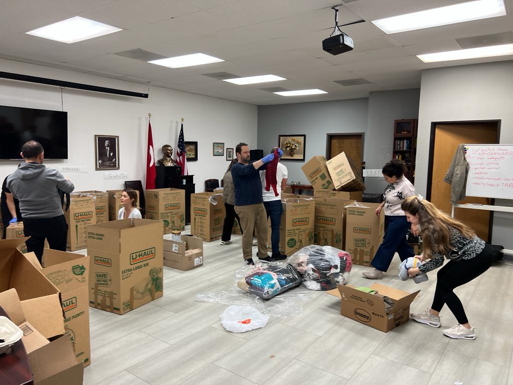 Volunteers filling shipping boxes with donated hats, scarves, and blankets